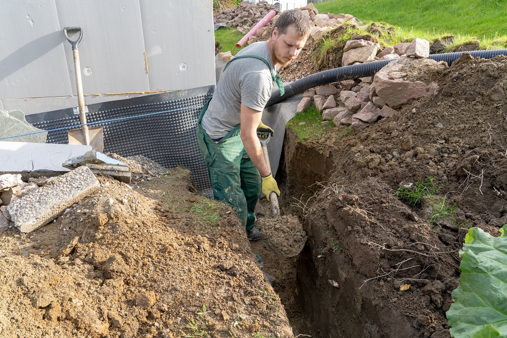 A man Digging ground to prepare to how to install french drain in basement